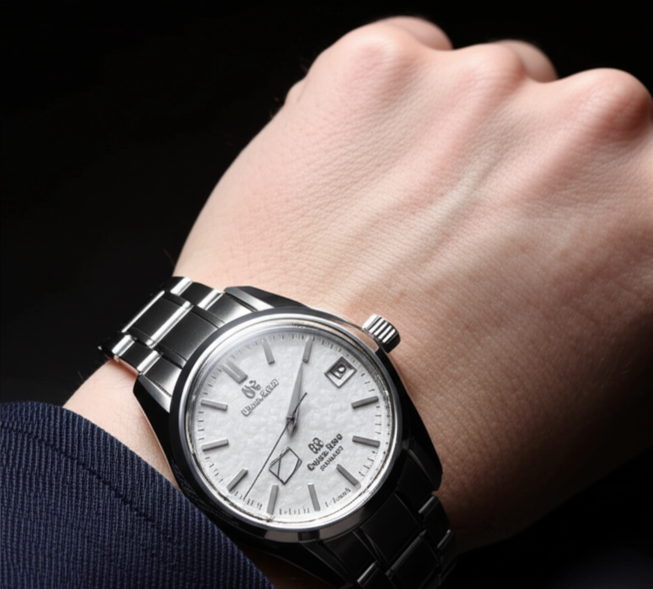 Immagine iperrealistica del polso di un uomo caucasico che indossa un orologio Grand Seiko 'Snowflake', con il quadrante ben visibile su una manica di blazer in cashmere blu scuro.