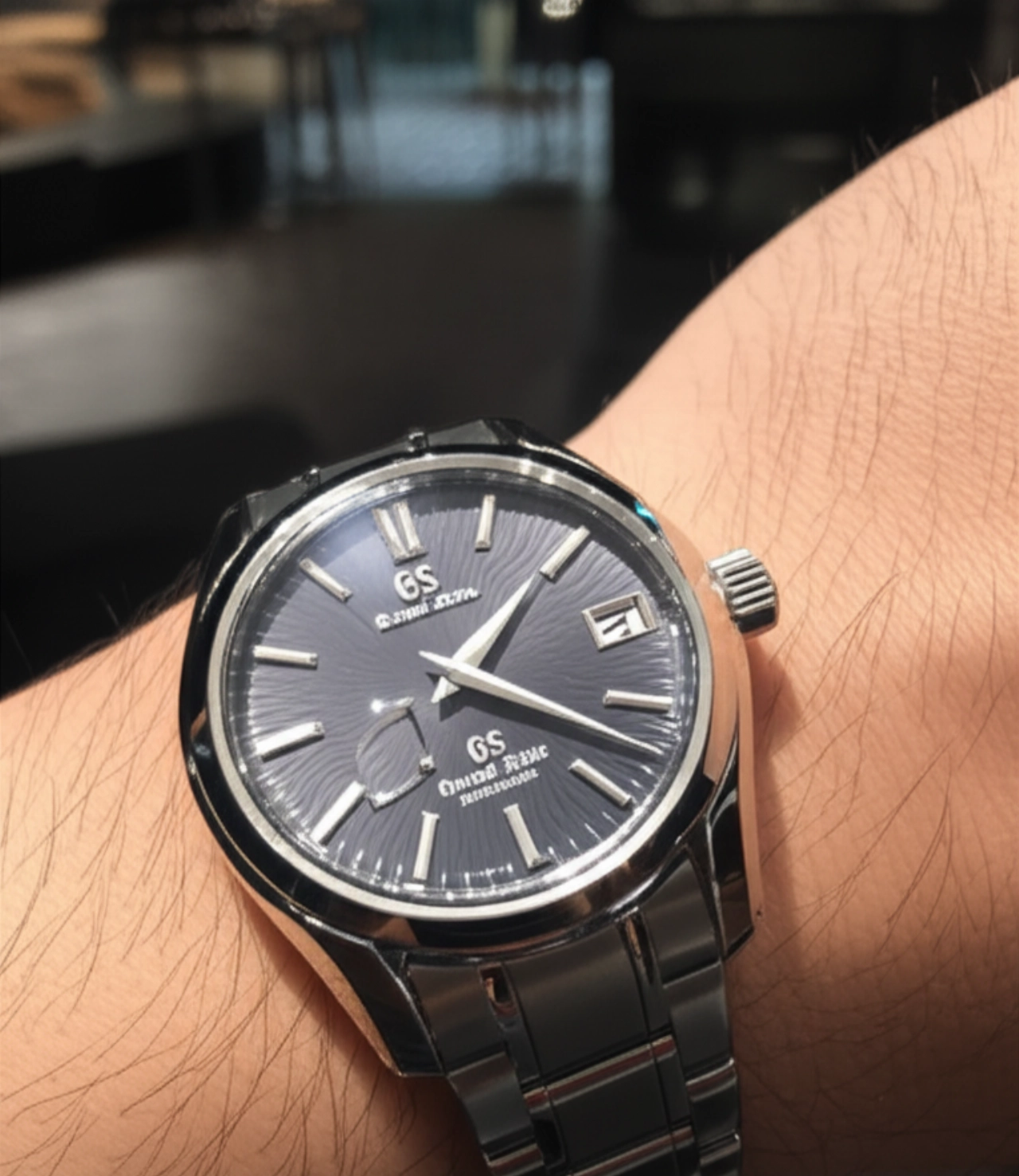Un elegante orologio Grand Seiko al polso di un individuo caucasico, che riflette l'artigianato superiore e la sofisticazione moderna.